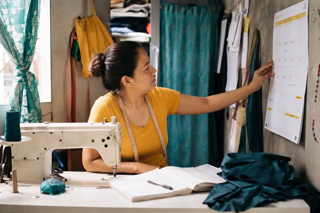 A woman reviewing a monthly planner in her tailoring workshop